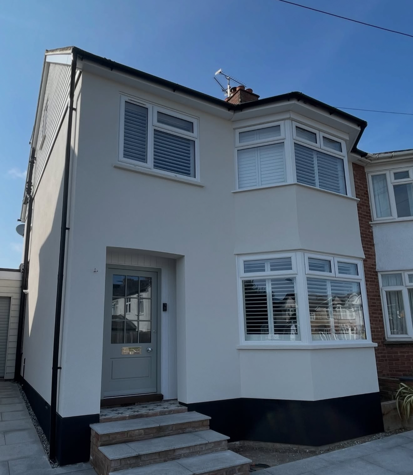 Rendered house front with white bay windows