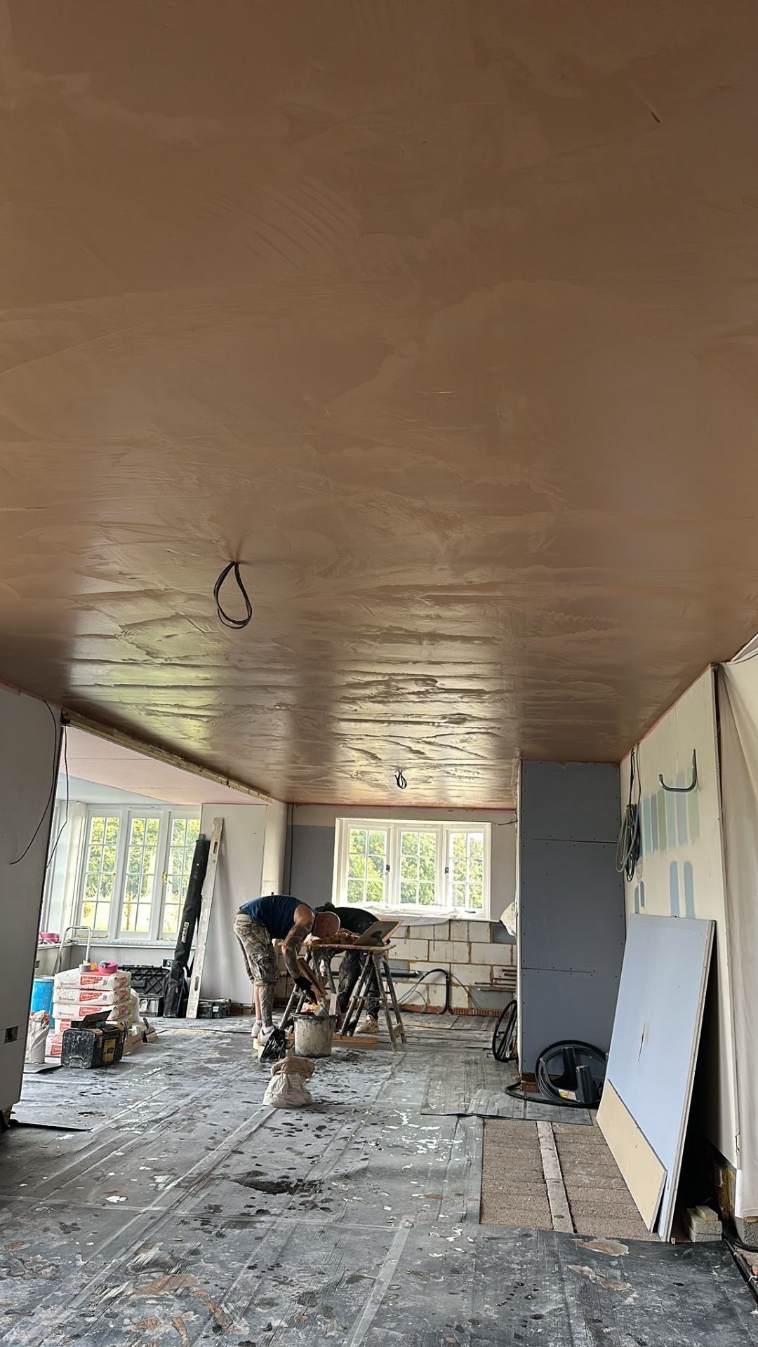 Long open-plan room with a plastered ceiling